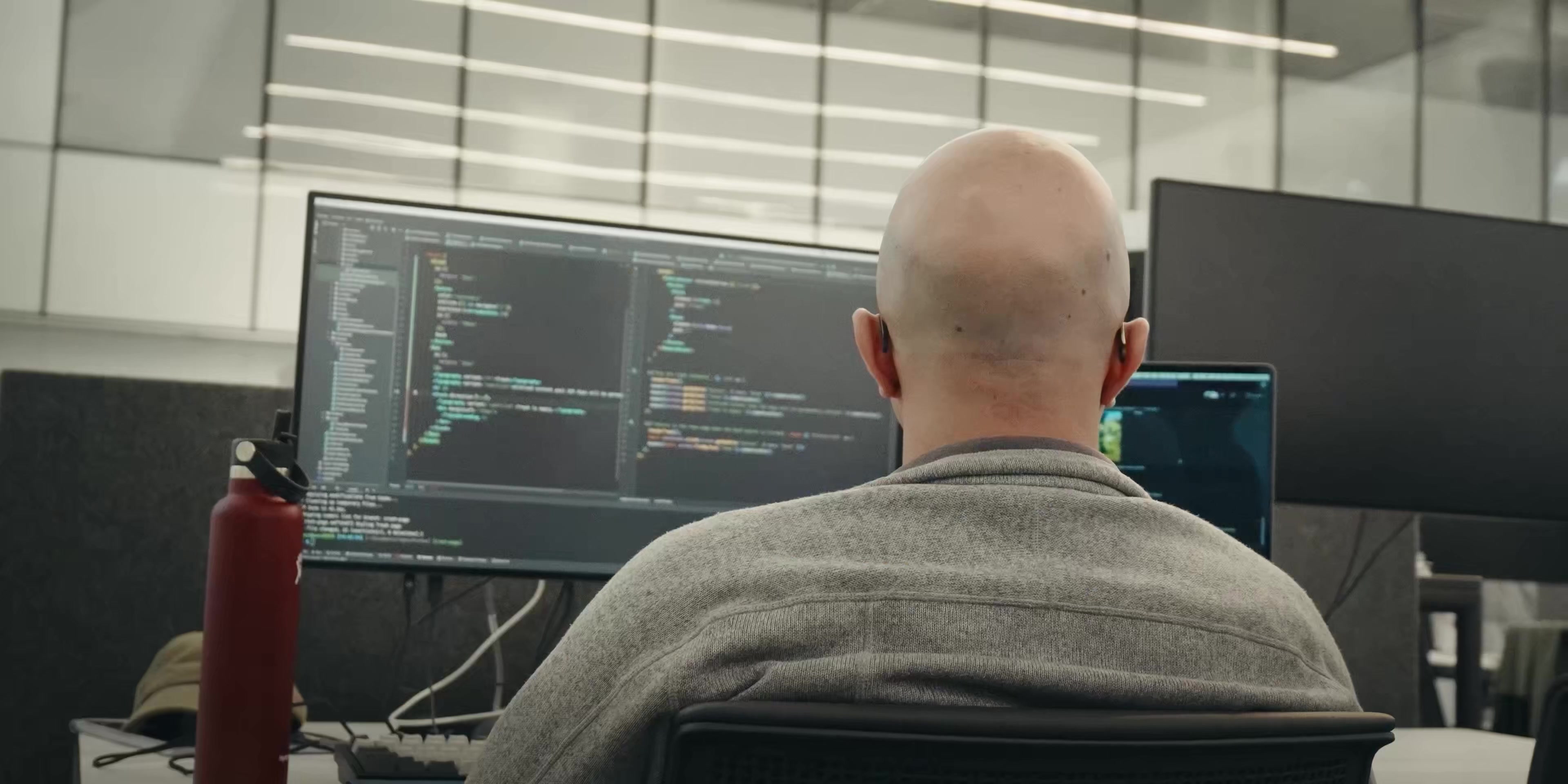 Developer studies code on multiple monitors.