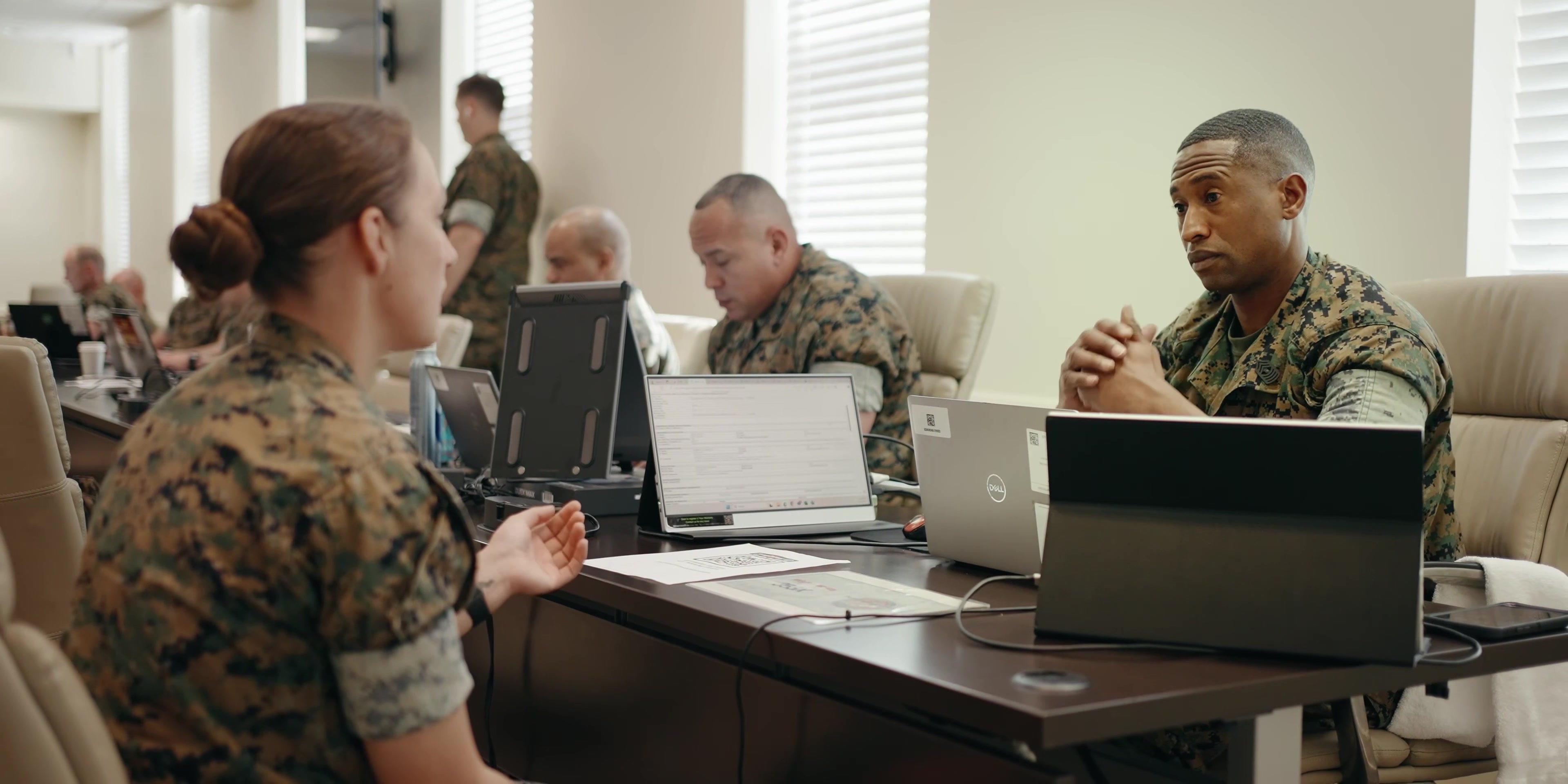 Uniformed colleagues discuss software and workflow at a table.