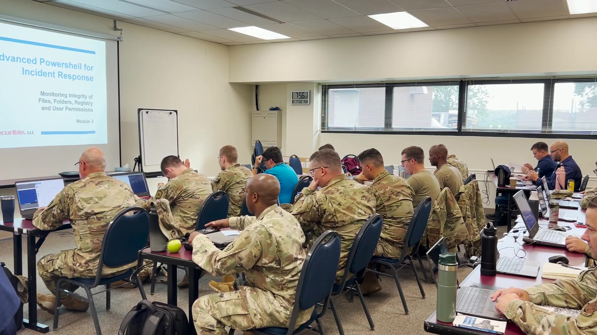 Civilian-clothed and uniformed participants work in the same technical classroom.