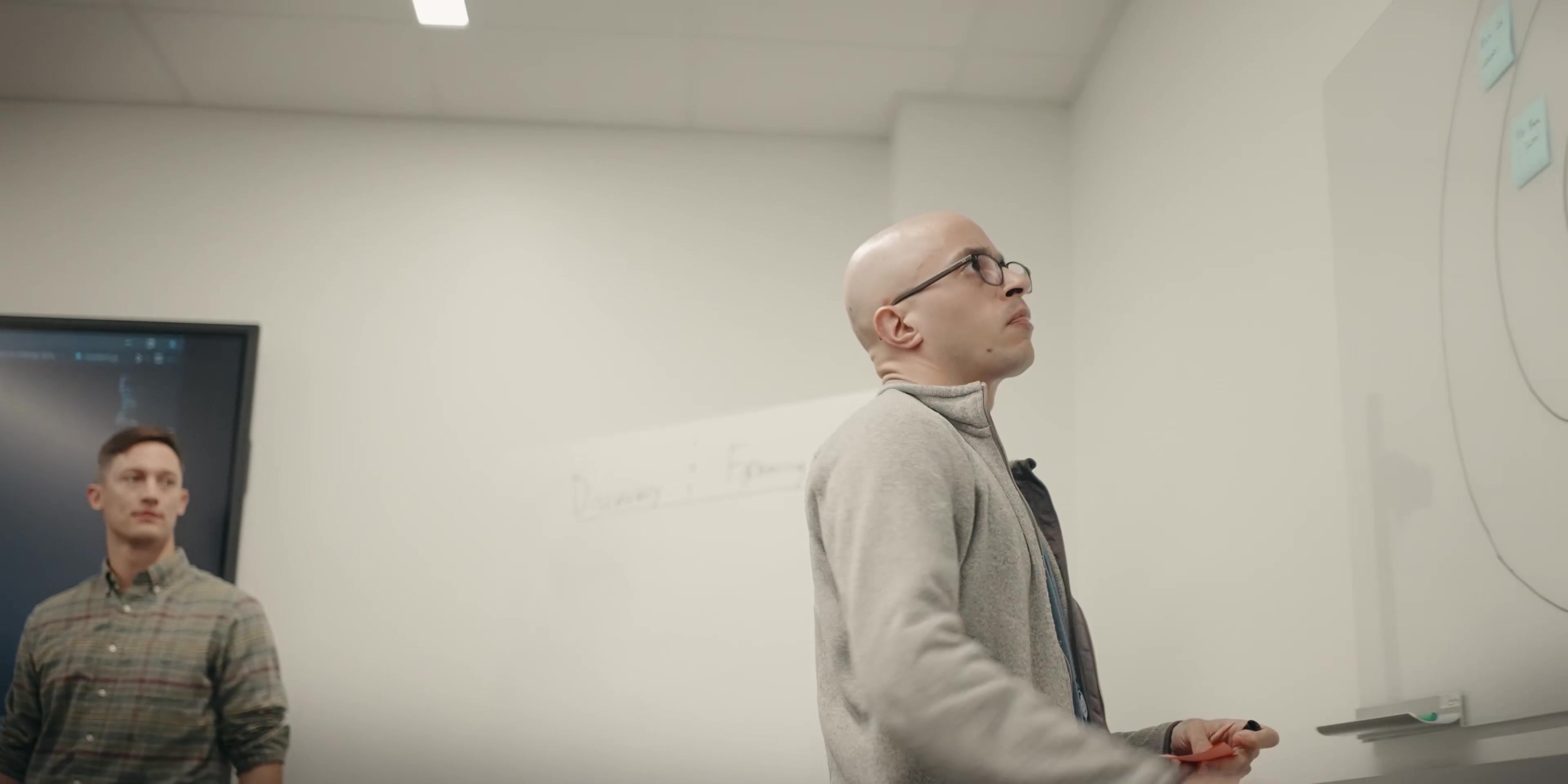Civilian-clothed colleagues work at a software-development whiteboard.